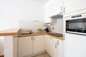 a white kitchen with a sink and a microwave at Cosy condo in the city centre in Ostend
