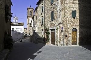 un callejón con un gran edificio de piedra con una torre de reloj en La Casina di Neda, en Civitella Marittima