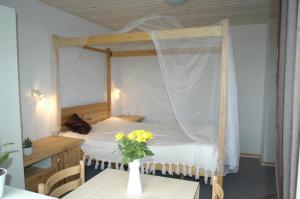 - une chambre avec un lit à baldaquin et un vase de fleurs sur une table dans l'établissement Henne Strand Ferie Accommodation, à Hennebjerg