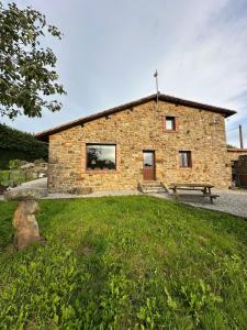 a stone building with a bench in front of it at Casa Rural El Entamáu in Argüero