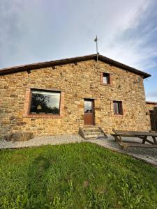 a stone building with a bench in front of it at Casa Rural El Entamáu in Argüero