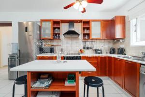 a kitchen with wooden cabinets and a kitchen island with stools at Apartment Olive in Paralimni
