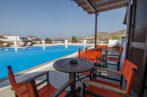 a patio with a table and chairs next to a swimming pool at Golden Sun in Ios Chora