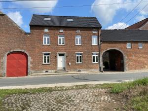 a brick building with a red door and a street at La ruche - maison de 10 à 15 personnes - La Ferme du Try in Frasnes-lez-Gosselies