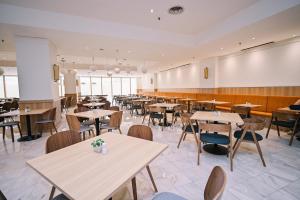 a dining room with tables and chairs and windows at Kingston Hotel 10 - Bukit Jalil in Serdang