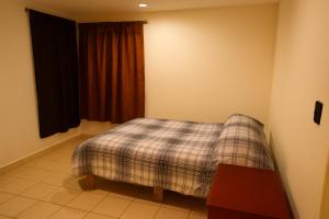 a bedroom with a plaid bed in a room at Nova Stay Puebla in La Concepción
