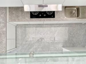 een badkamer met een wastafel en een magnetron bij De Residence Pangandaran by Mabano Estates in Pangandaran