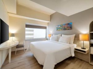 una camera da letto bianca con un letto grande e una scrivania di Artotel Harmoni Jakarta a Giacarta