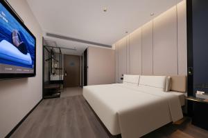 Atour Hotel Shanghai Jing'an North XIzang Road Metro Station في شانغهاي: غرفة نوم بسرير ابيض وتلفزيون بشاشة مسطحة +20 صورة