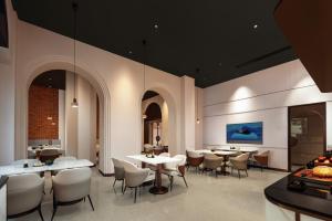 Atour Hotel Shanghai Jing'an North XIzang Road Metro Station في شانغهاي: غرفة طعام مع طاولات وكراسي بيضاء