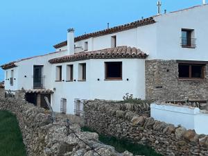 a white house with a stone wall at Masia El Nido in Villafranca del Cid