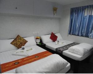 Cette chambre comprend 3 lits et une fenêtre. dans l'établissement City Guest House, à Hong Kong
