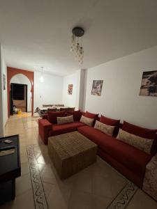 a living room with a red couch and a table at Luxueuse à Marina Saidia in Saïdia