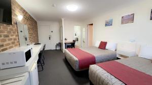 a hotel room with two beds and a desk at Top of the Town Motel in Inverell