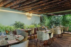 a restaurant with tables and chairs and plants at Hotel Nani Mocenigo Palace in Venice