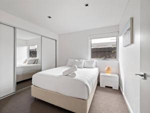 Un dormitorio blanco con una cama grande y un espejo. en Allure - Easy Beachside Living in Prime Location, en Dunsborough