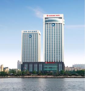 two tall buildings in a city next to the water at Haiwaihai Grand Hotel Ma'anshan in Ma'anshan
