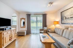 a living room with a couch and a tv at Fewo Brünnstein - Nr 13 Pool, Sauna in Oberaudorf