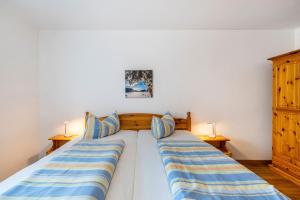 a bedroom with two beds with blue and yellow striped pillows at Fewo Brünnstein - Nr 61 Pool, Sauna in Oberaudorf