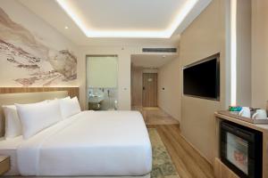 a bedroom with a large white bed and a television at Riviera Sarovar Portico Pathankot in Pathānkot