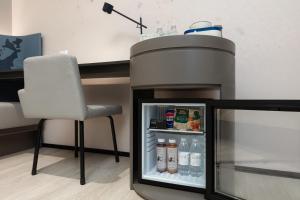 Atour Hotel Shanghai Wujiaochang Huangxing Road Subway Station في شانغهاي: وجود ثلاجة وكرسي في الغرفة