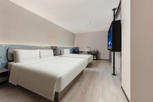 Atour Hotel Shanghai Wujiaochang Huangxing Road Subway Station في شانغهاي: غرفة نوم بها سرير أبيض كبير وتلفزيون بشاشة مسطحة