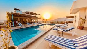 a pool at a hotel with chairs and the sunset at Thebes Hotel in Luxor