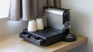 a black hair dryer sitting on a shelf with towels at Campanile PRIME - Arcueil in Arcueil