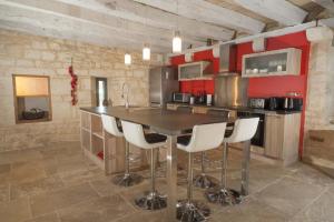 Una cocina con una mesa de madera y taburetes blancos. en La floridienne, en La Cassagne