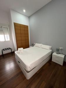 a bedroom with a white bed and a wooden floor at Apartment Plaza de la Merced in Valencia