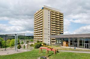 Un edificio alto con un parque infantil delante del edificio. en Superior App 238 mit Pool und Sauna, en Braunlage