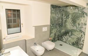 a bathroom with a white toilet and a green leaf wallpaper at Aosta Holiday Apartments - Croix-de-Ville in Aosta +17 photos