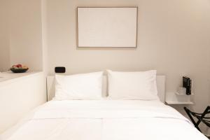a white bed with white pillows in a bedroom at Skyline Cube in Thessaloniki