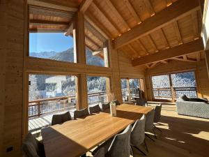 a large wooden table and chairs in a room with windows at CHALET ALIET 1500 - 18 personnes PEISEY NANCROIX - LES ARCS - LA PLAGNE - PARADISKI in Peisey-Nancroix