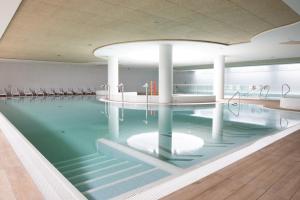 a swimming pool with green water and white columns at PINEA Resort in Pobierowo