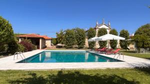 a swimming pool with two chairs and an umbrella at Feel Discovery Casa Da Capela Douro Valley in Armamar