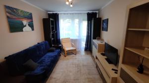 a living room with a blue couch and a tv at Apartament pod Górą Chełmską in Koszalin