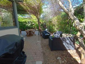 d'une terrasse avec une table, des chaises et un arbre. dans l'établissement Maison provençale avec piscine partagée, à Loriol-du-Comtat