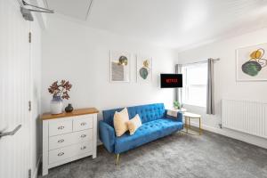 ein Wohnzimmer mit einem blauen Sofa und einer Kommode in der Unterkunft Aurum House Luxury Apartments in Blackpool