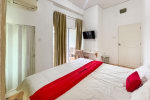 una camera da letto con un grande letto bianco con lenzuola rosse di RedDoorz at Kanaka Hostel Tanjung Pinang a Tanjung Pinang Altre 16 foto