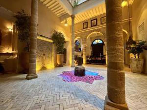 eine Lobby mit einem Brunnen in der Mitte eines Raumes in der Unterkunft Riad MALAÏKA in Essaouira