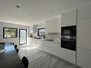 a kitchen with white cabinets and a table with chairs at Villa Seixo - Spa, Beach and Nature in A dos Cunhados
