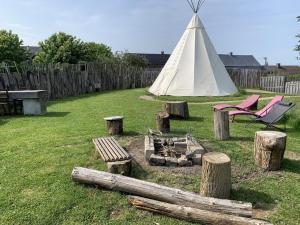 a tent and a chair in a yard with logs at Le tipi d'Adri in Gesves