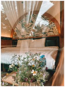 a bedroom with a bed and a table with flowers at Nam garden lodge in Tân Phú