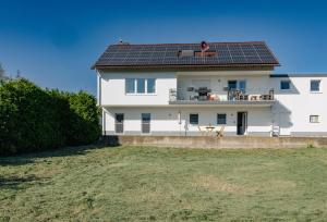 a white house with solar panels on the roof at Bürgstadt, Am Bischof mit Sonnenterrasse, 1 bis 4 Betten in Buergstadt