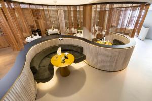 a lobby with a yellow table and a room with chairs at Hotel Das Innsbruck in Innsbruck