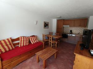 a living room with a red couch and a table at Appartement au Pied des Pistes - Tout Confort - Grande Terrasse Sud - FR-1-445-190 in Montgenèvre