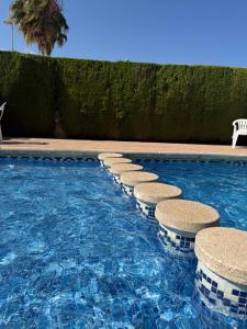 a swimming pool with a row of stools in the water at Costa Oasis Residencia La Mirada in Orihuela Costa