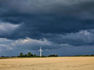 a wind turbine in a field under a cloudy sky at Ferienwohnung Fehnzauber, 86005 in Ostrhauderfehn