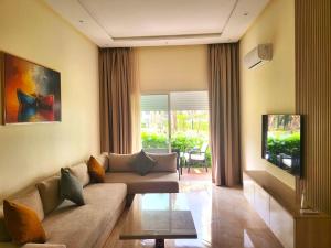 a living room with a couch and a tv at Superbe appartement à bouznika avec vue sur piscine et jardin privatif in Bouznika